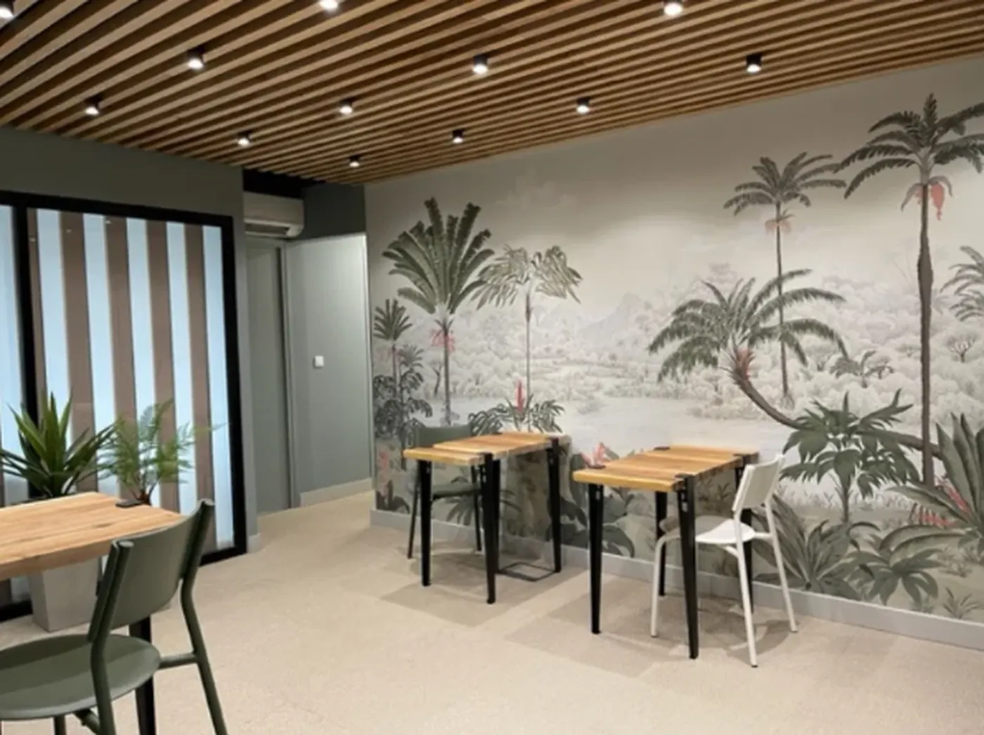 Espace de pause avec tables hautes et fresque végétale